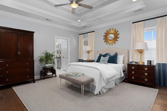 bedroom featuring ornamental molding, light wood-type flooring, a raised ceiling, and visible vents