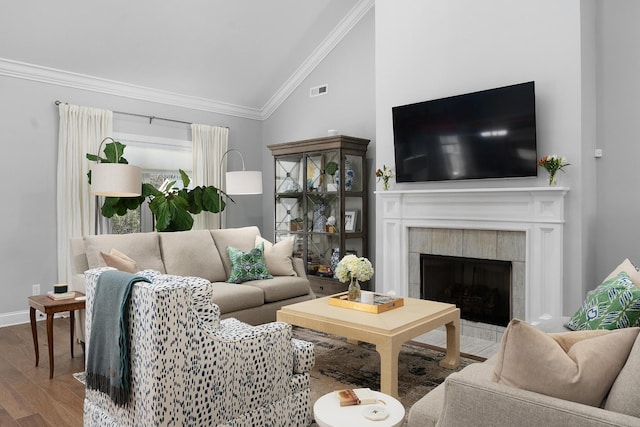 living area featuring a fireplace, crown molding, vaulted ceiling, wood finished floors, and baseboards