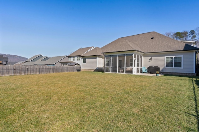 rear view of property with a lawn, fence, and a sunroom