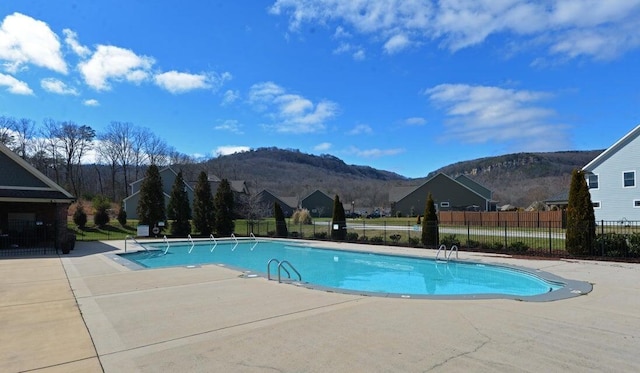 pool with a patio area, fence, and a mountain view