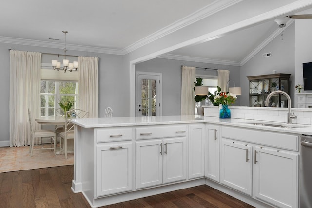 kitchen with dark wood-type flooring, a sink, light countertops, ornamental molding, and an inviting chandelier