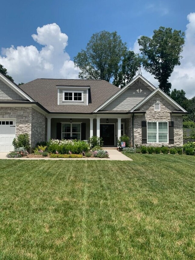 craftsman inspired home with an attached garage, stone siding, and a front yard