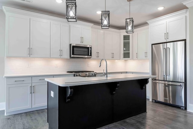 kitchen featuring a kitchen island with sink, appliances with stainless steel finishes, light countertops, and dark wood finished floors