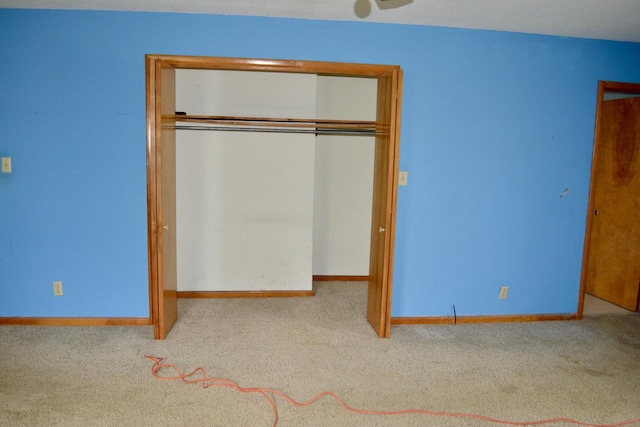 unfurnished bedroom with a closet, carpet flooring, and baseboards