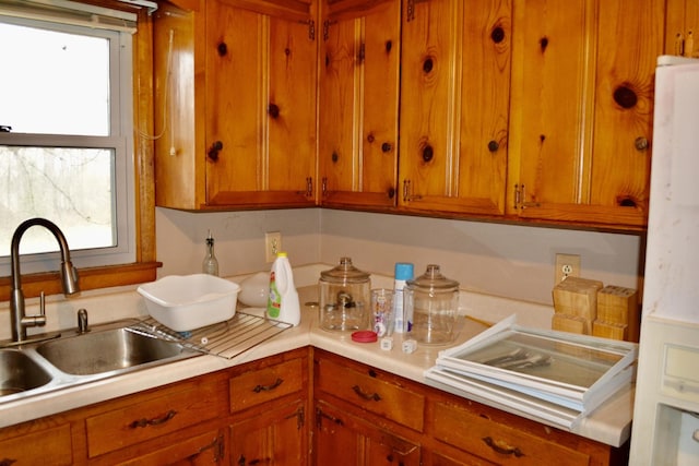 kitchen with light countertops, plenty of natural light, brown cabinets, and a sink