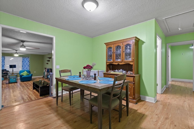 dining space with a textured ceiling, light wood finished floors, attic access, and baseboards