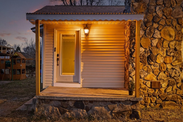 exterior entry at dusk with a shingled roof