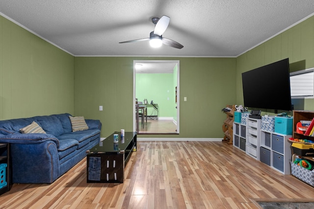 living area featuring a textured ceiling, ornamental molding, wood finished floors, and a ceiling fan