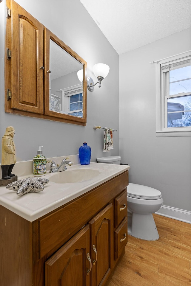 bathroom with baseboards, vanity, toilet, and wood finished floors