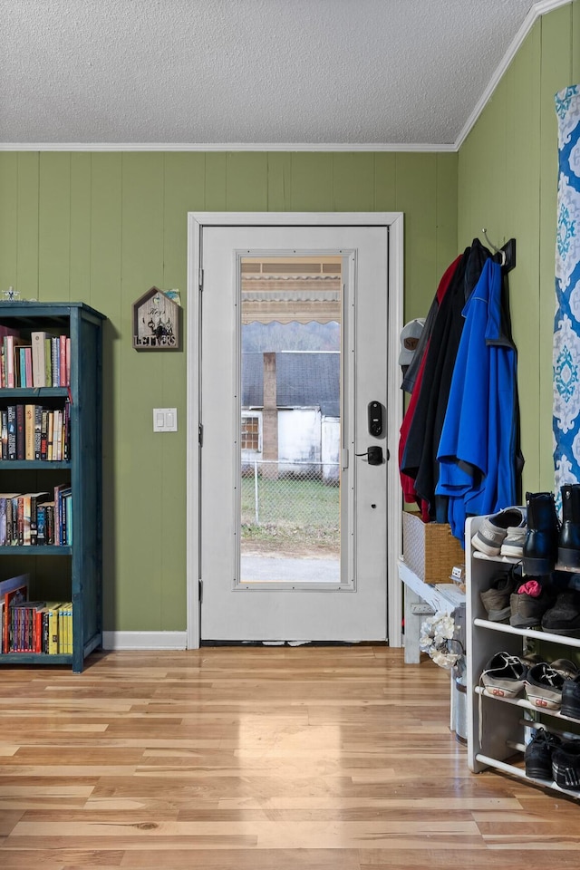 doorway to outside featuring crown molding, a textured ceiling, and wood finished floors