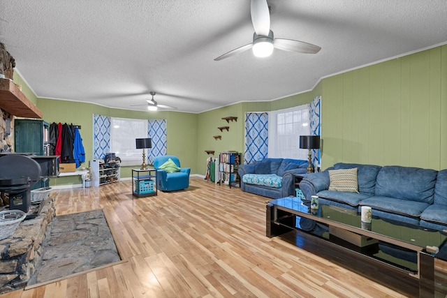 living area featuring ceiling fan, a textured ceiling, ornamental molding, and wood finished floors