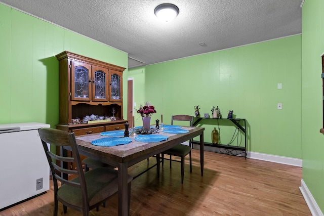 dining area featuring a textured ceiling, wood finished floors, and baseboards