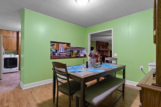 dining space with a textured ceiling, wood finished floors, washer / dryer, and baseboards