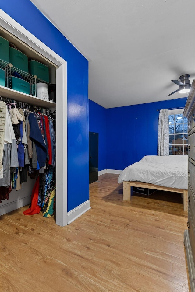 bedroom with a closet, wood finished floors, a ceiling fan, and baseboards