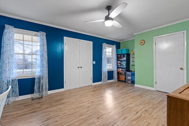 unfurnished bedroom featuring ceiling fan, visible vents, crown molding, and wood finished floors