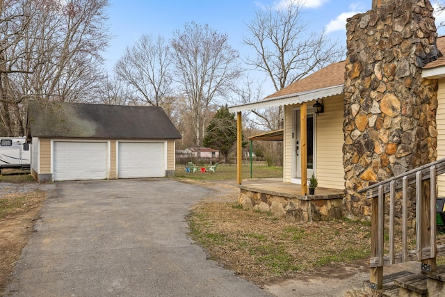 view of side of home featuring an outbuilding, roof with shingles, and a garage