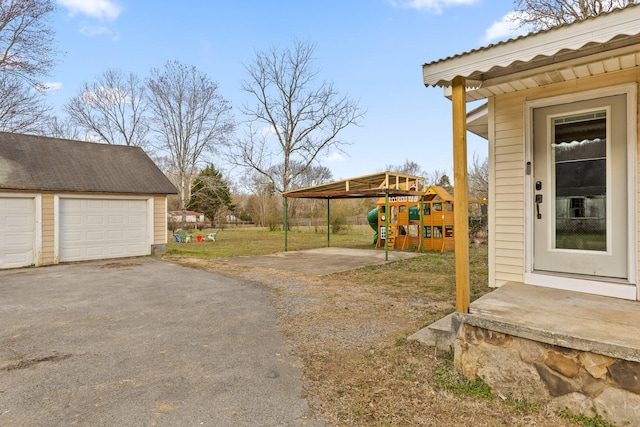 view of yard featuring a garage, a playground, and an outdoor structure