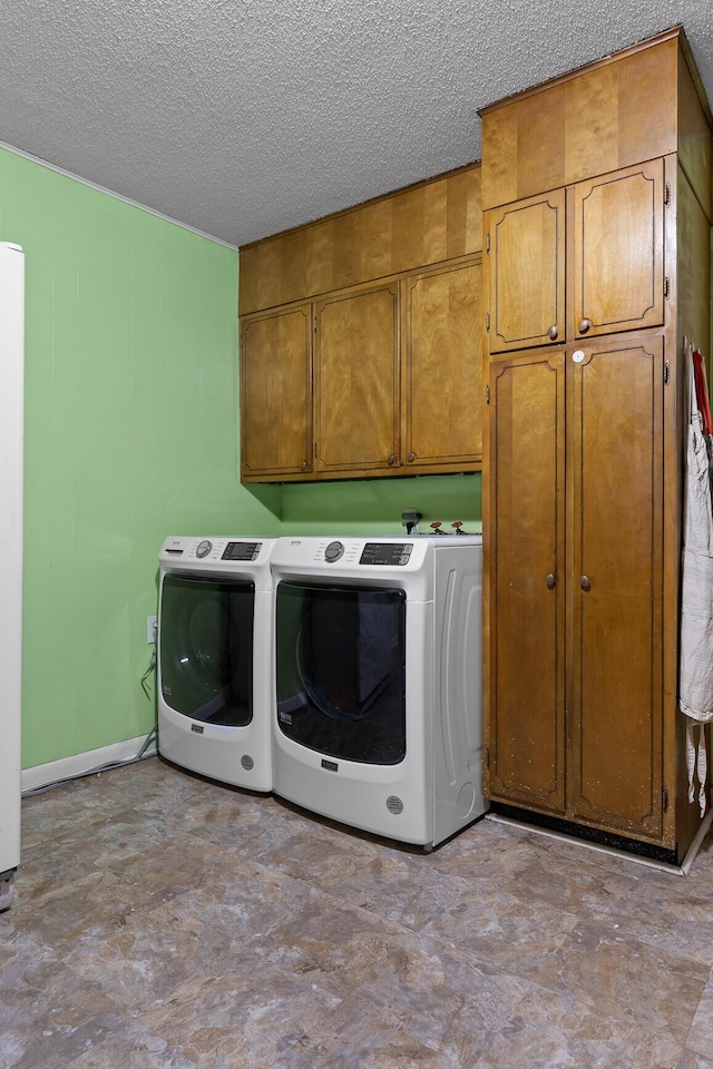 laundry room with washing machine and dryer, cabinet space, and a textured ceiling