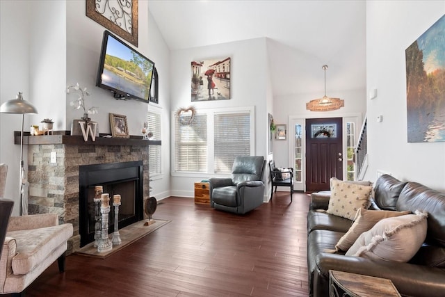 living area featuring high vaulted ceiling, wood finished floors, a stone fireplace, baseboards, and stairs