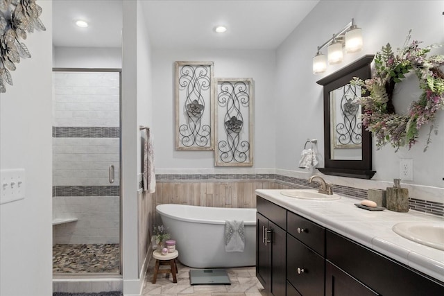 full bathroom with double vanity, a soaking tub, a stall shower, and a sink