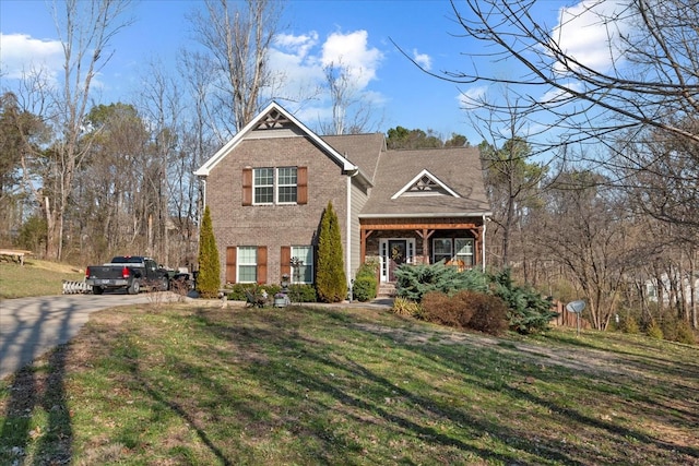 traditional home featuring concrete driveway, brick siding, and a front yard