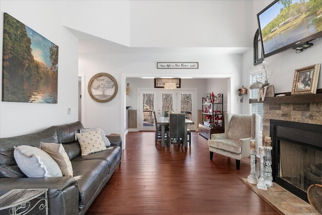 living area featuring a healthy amount of sunlight, a fireplace, a high ceiling, and wood finished floors