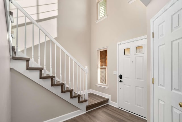 entryway featuring stairs, wood finished floors, a towering ceiling, and baseboards