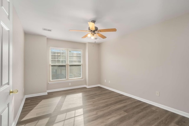 spare room featuring a ceiling fan, dark wood-style flooring, visible vents, and baseboards