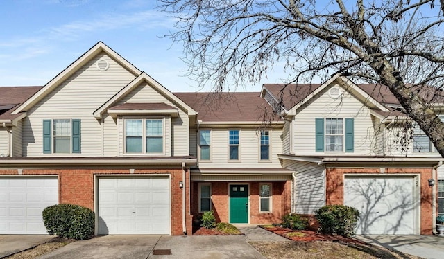 multi unit property featuring an attached garage, concrete driveway, and brick siding