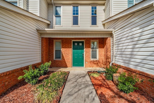 doorway to property with covered porch and brick siding