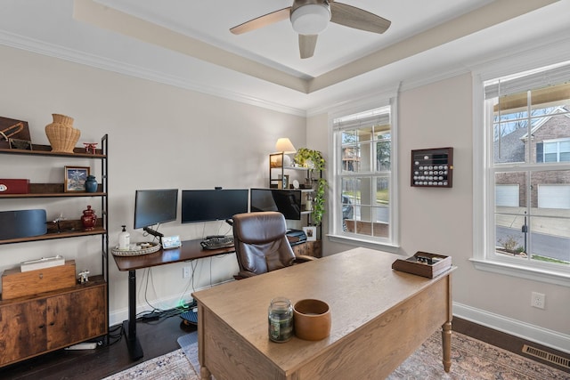 office space with a tray ceiling, visible vents, baseboards, and wood finished floors