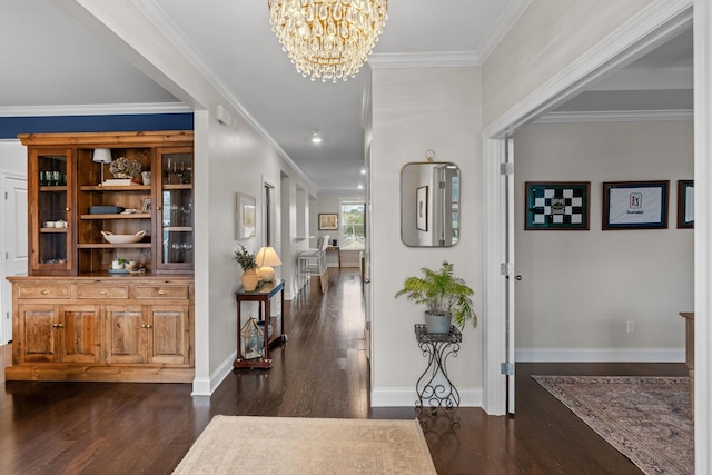 entrance foyer with dark wood-style floors, baseboards, ornamental molding, and an inviting chandelier