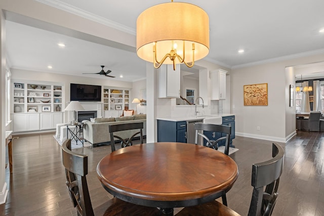 dining room featuring a fireplace, ornamental molding, dark wood-type flooring, and ceiling fan with notable chandelier