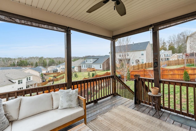 wooden terrace with outdoor lounge area, fence, a ceiling fan, a lawn, and a residential view