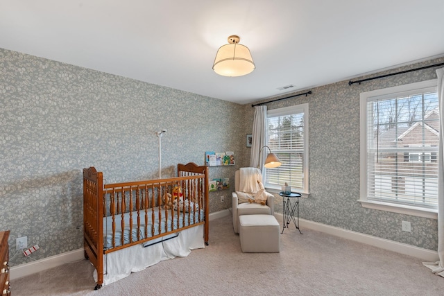 carpeted bedroom with wallpapered walls, baseboards, visible vents, and a nursery area