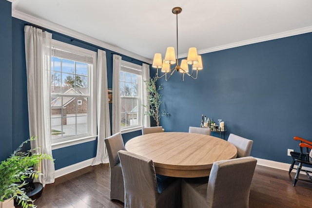 dining area featuring ornamental molding, dark wood-type flooring, a notable chandelier, and baseboards