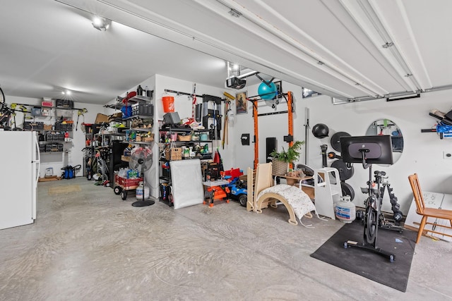 garage with a workshop area, freestanding refrigerator, and a garage door opener