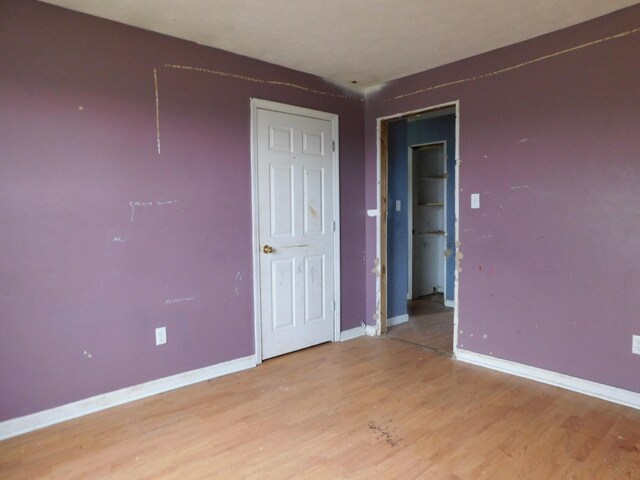 spare room featuring baseboards and light wood finished floors