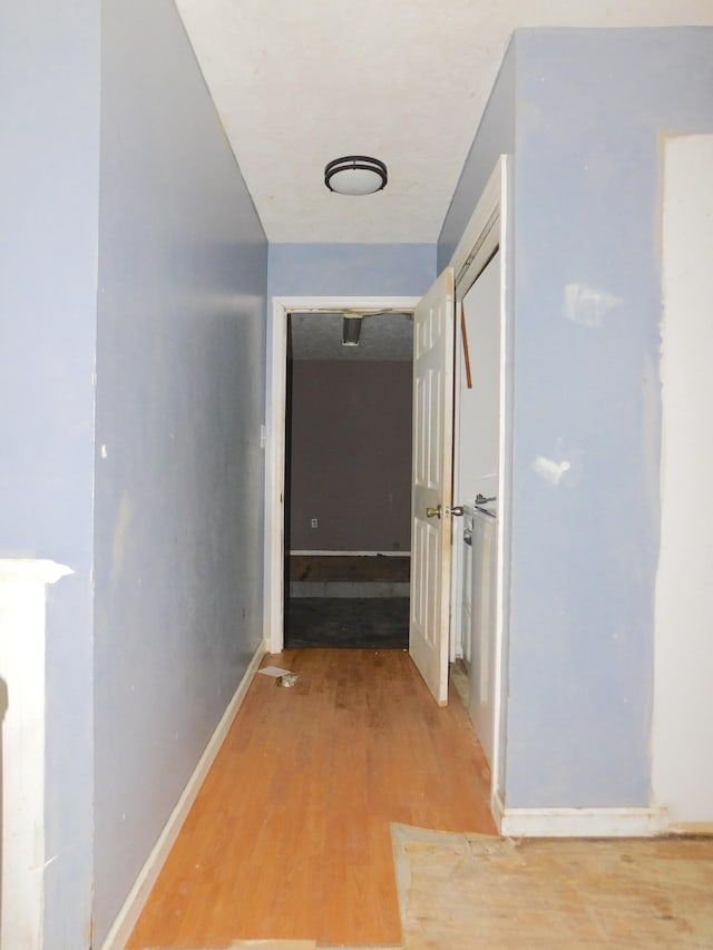 hallway featuring light wood-style flooring and baseboards