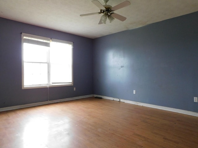 empty room featuring ceiling fan, wood finished floors, and baseboards