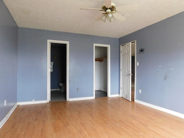 unfurnished bedroom featuring a ceiling fan, wood finished floors, connected bathroom, and baseboards