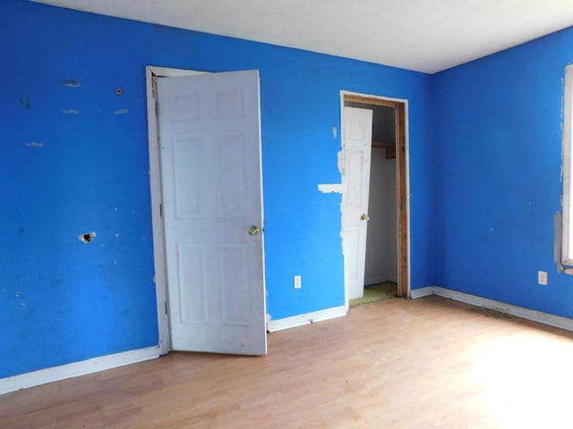 unfurnished bedroom with a closet, light wood-style flooring, and baseboards