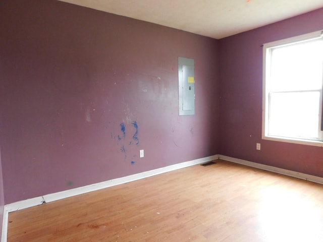 spare room with visible vents, light wood-style flooring, electric panel, and baseboards