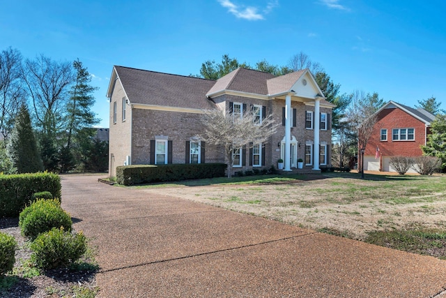 neoclassical / greek revival house with a front yard and brick siding