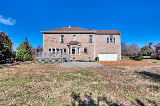 rear view of house featuring brick siding, a yard, crawl space, a deck, and a garage
