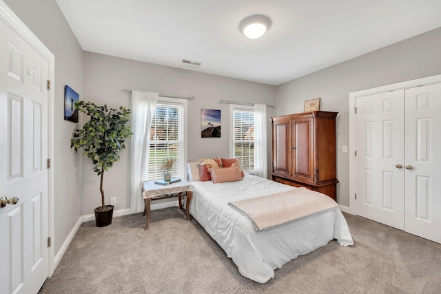 bedroom featuring baseboards, visible vents, a closet, and light colored carpet