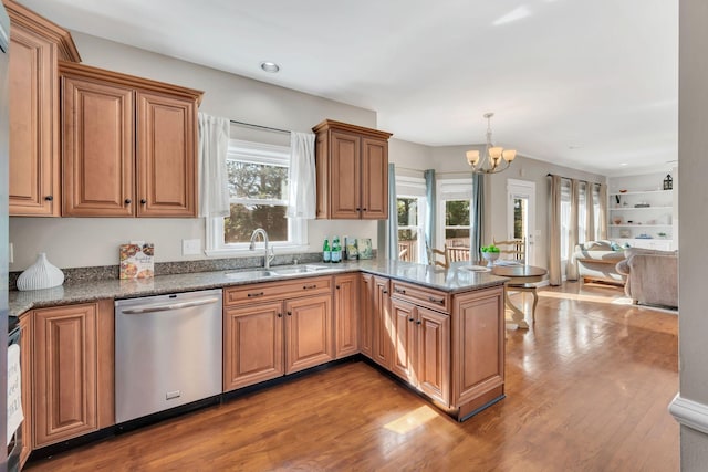 kitchen with a notable chandelier, a peninsula, a sink, stainless steel dishwasher, and light wood finished floors