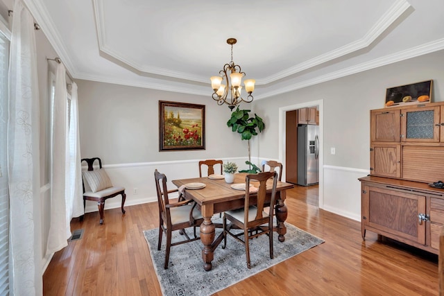 dining space featuring visible vents, crown molding, light wood-style flooring, and an inviting chandelier