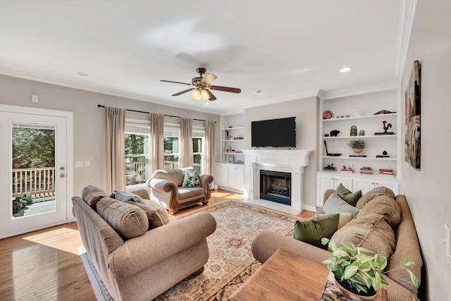living room featuring ornamental molding, built in features, a fireplace, and light wood finished floors