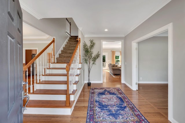 entryway featuring crown molding, stairs, baseboards, and wood finished floors